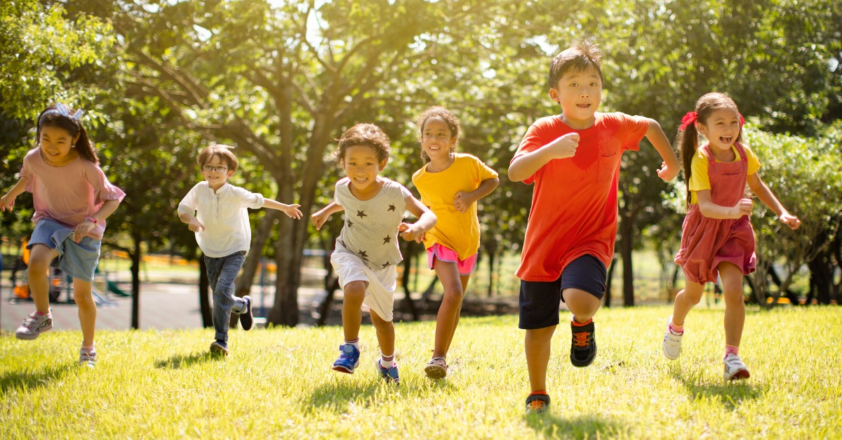 multi ethnic group of school children laughing and running